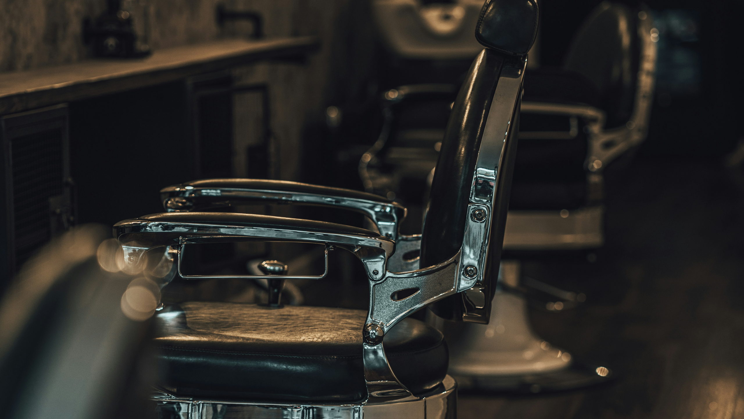 Row of chrome and leather barber chairs inside Fade & Barrel